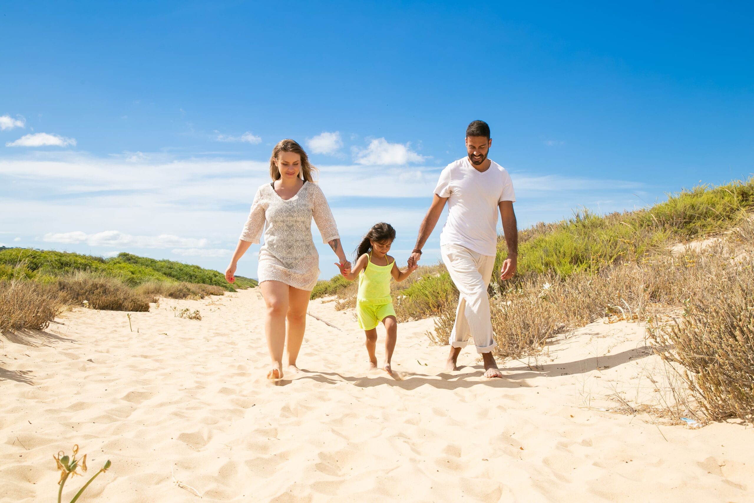 happy family couple little kid summer clothes walking white along sand path girl holding parents hands (1)